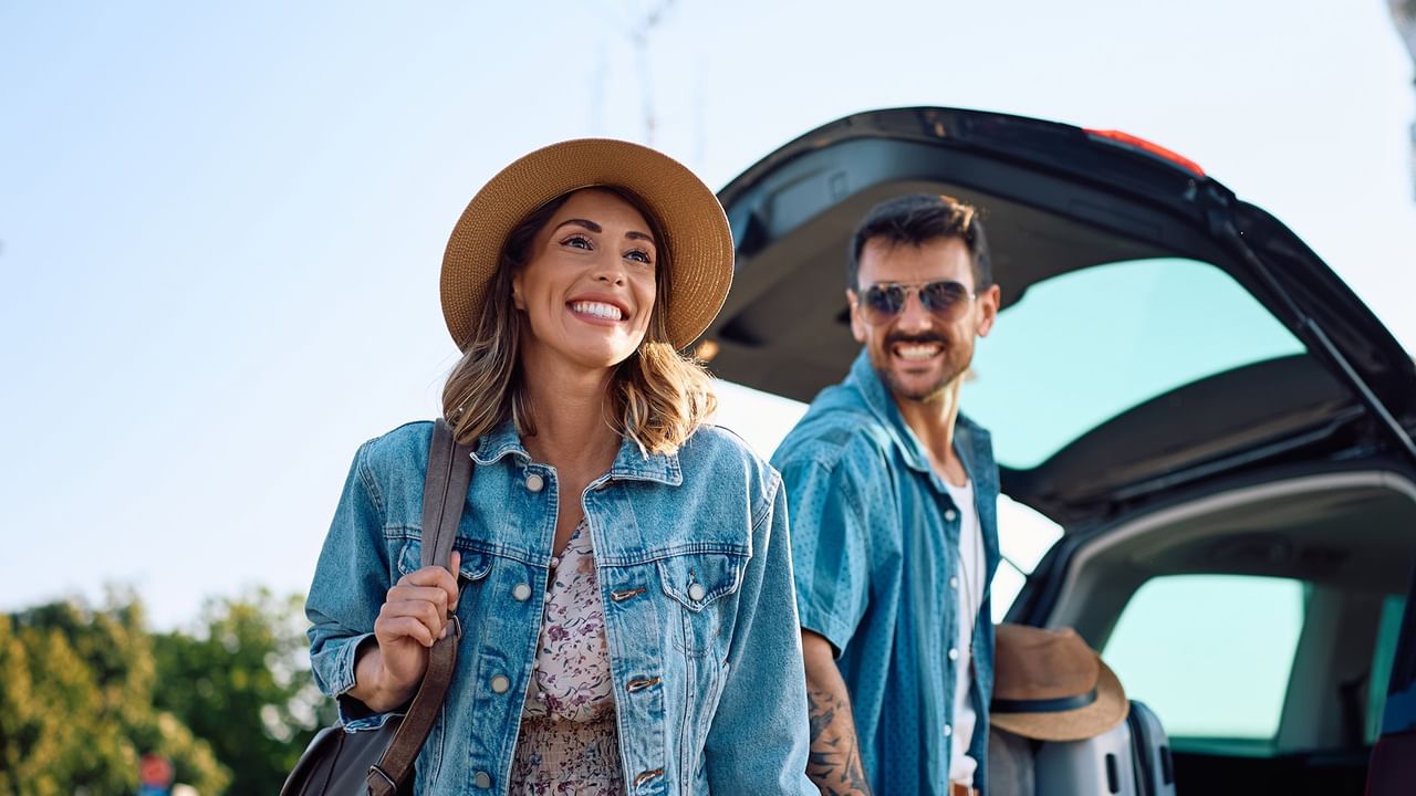 couple taking their luggage from a car