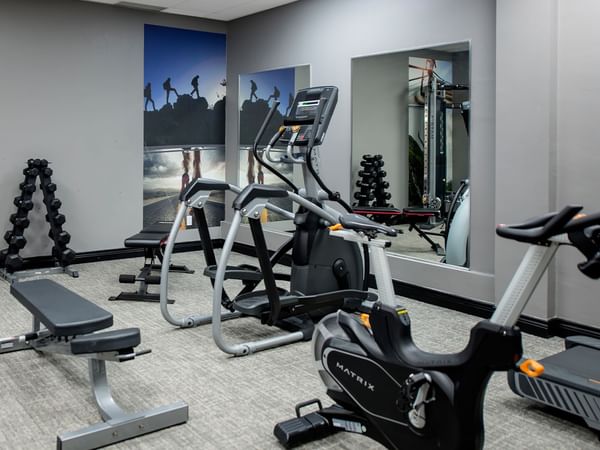 Hotel gym room with treadmills, stationary bike, weight bench, and weight rack.