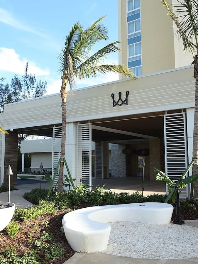 White curved bench by a fire pit under palm trees surrounding the entrance at Warwick Paradise Island Bahamas