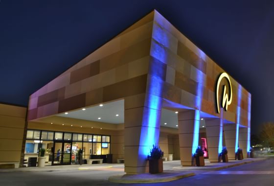 Hotel entrance with a brightly illuminated portico and Rosen logo above the driveway at night at Rosen Inn International