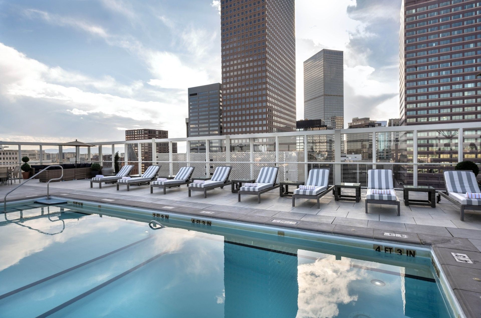 A rooftop pool with lounge chairs and a city skyline view.