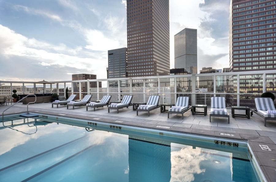 Guest swimming in the rooftop pool near loungers under the bright sun at Warwick Denver