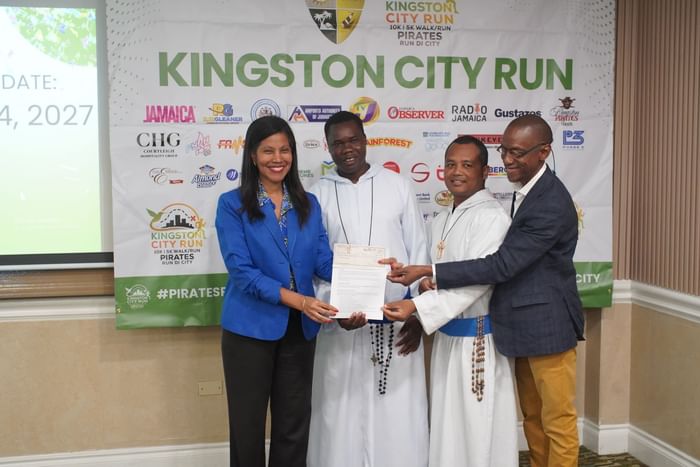 Group presenting a sponsorship check in front of the Kingston City Run banner at Courtleigh Hotel & Suites
