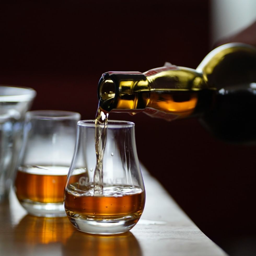 Close-up of pouring whisky into glasses, Falkensteiner Hotels