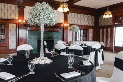 Banquet hall set up with black and white decor, round tables with floral centerpieces, and wooden walls at The Stanley Hotel