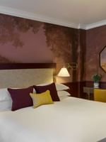 Executive King room with forest-themed wallpaper, elegant bedside lamps, and octagonal mirror at The Capital Hotel, London.