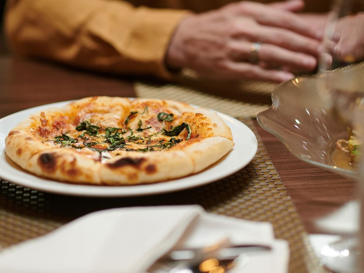 People dining with a pizza on a plate at Green Gables Restaurant & Lounge in Whitecourt at Coast Whitecourt Hotel.