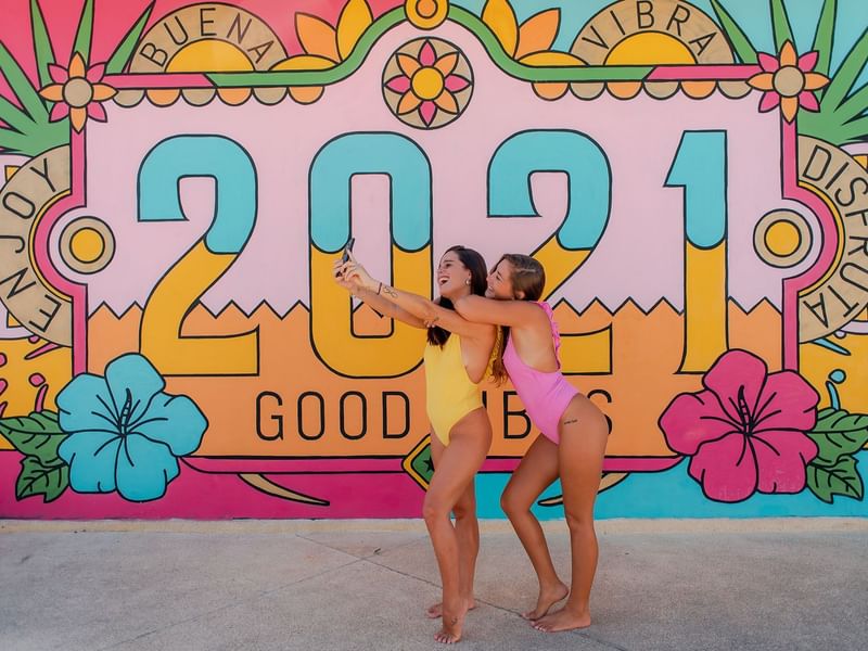 Close up on girls posing in front of 2021 art at The Reef 28
