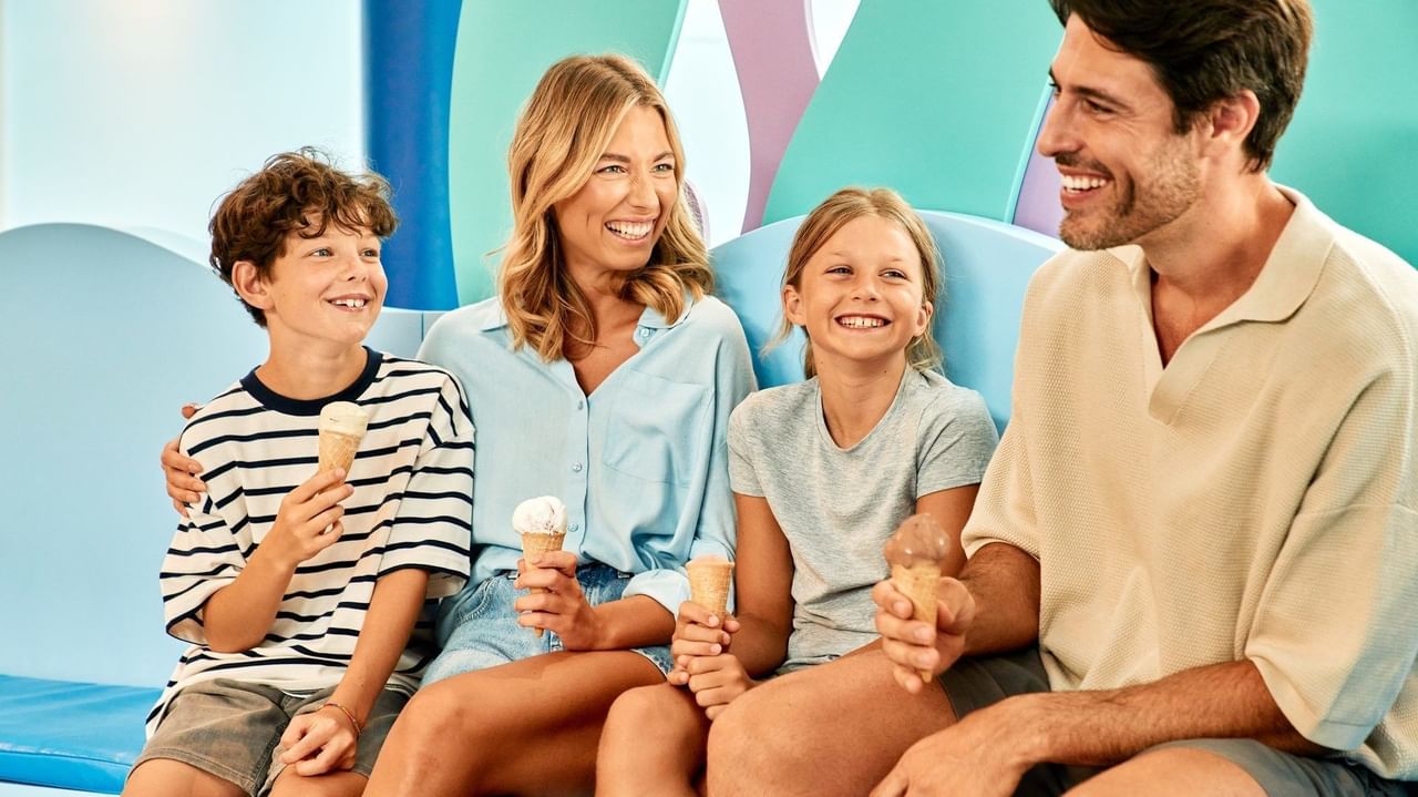 Famiglia felice con due bambini che mangia gelati su un sedile blu.