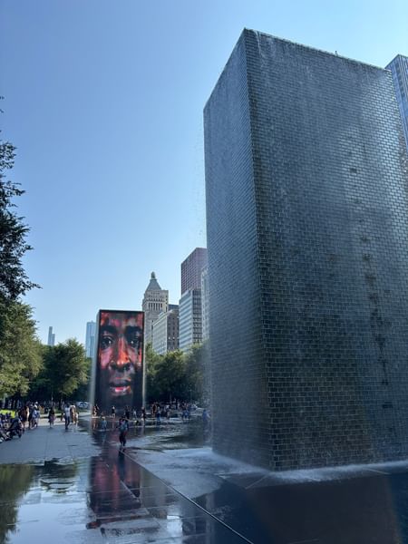 Water flowing down a large rectangular sculpture with people around near Warwick Allerton Chicago
