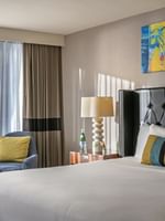 Emerald Suite with an armchair by a window and a tufted bed under art at Warwick Seattle