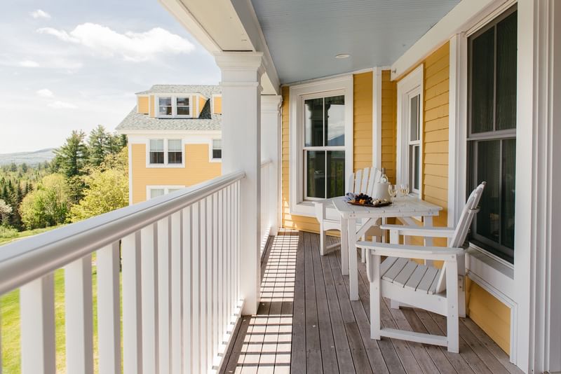 Balcony seating area with wooden table & chairs facing scenic outdoor landscape at Mountain View Grand Resort & Spa