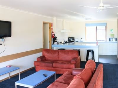 Living area with red couches and a kitchen at La Trobe University Terraces.