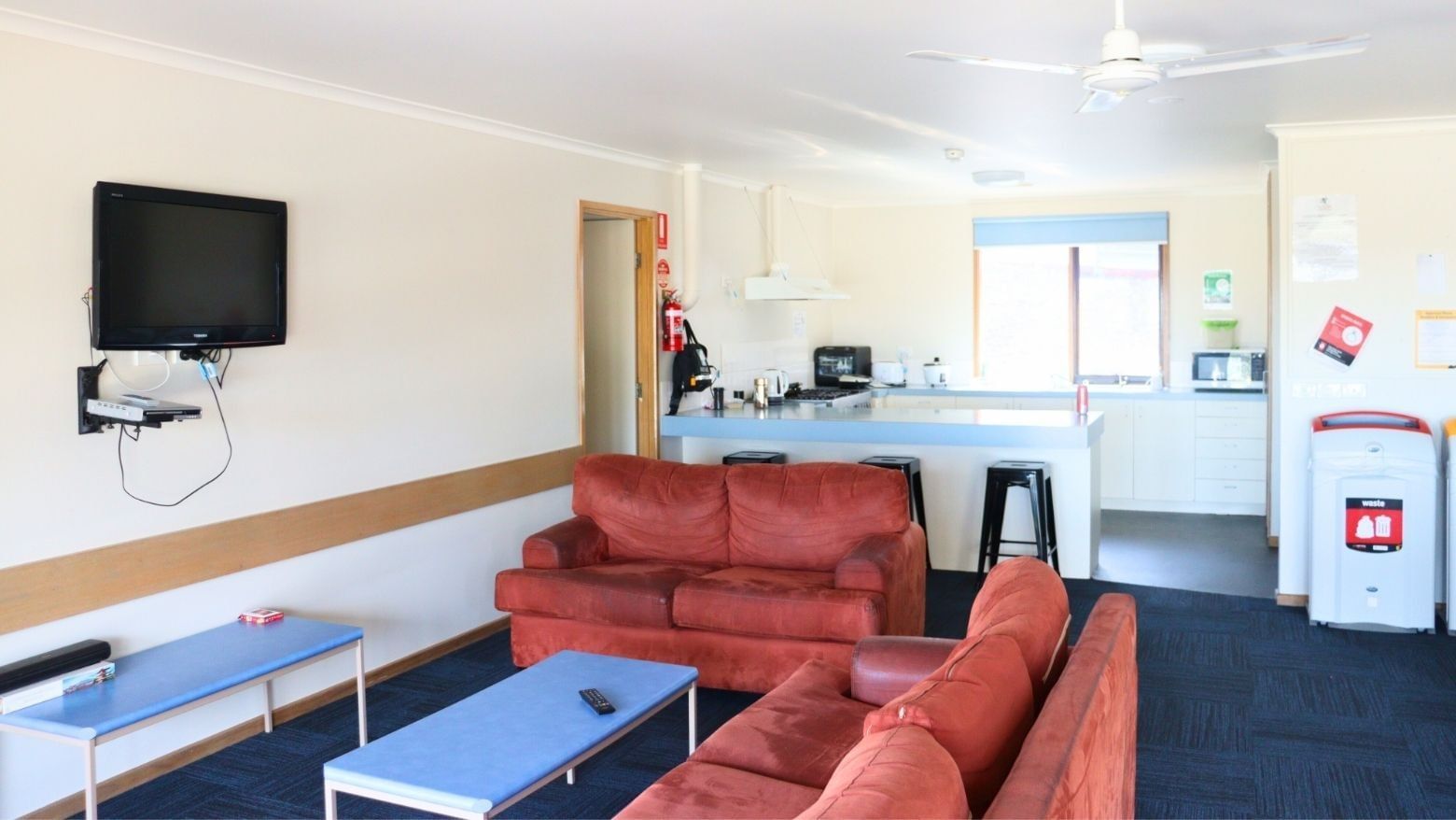Living area with red couches and a kitchen at La Trobe University Terraces.