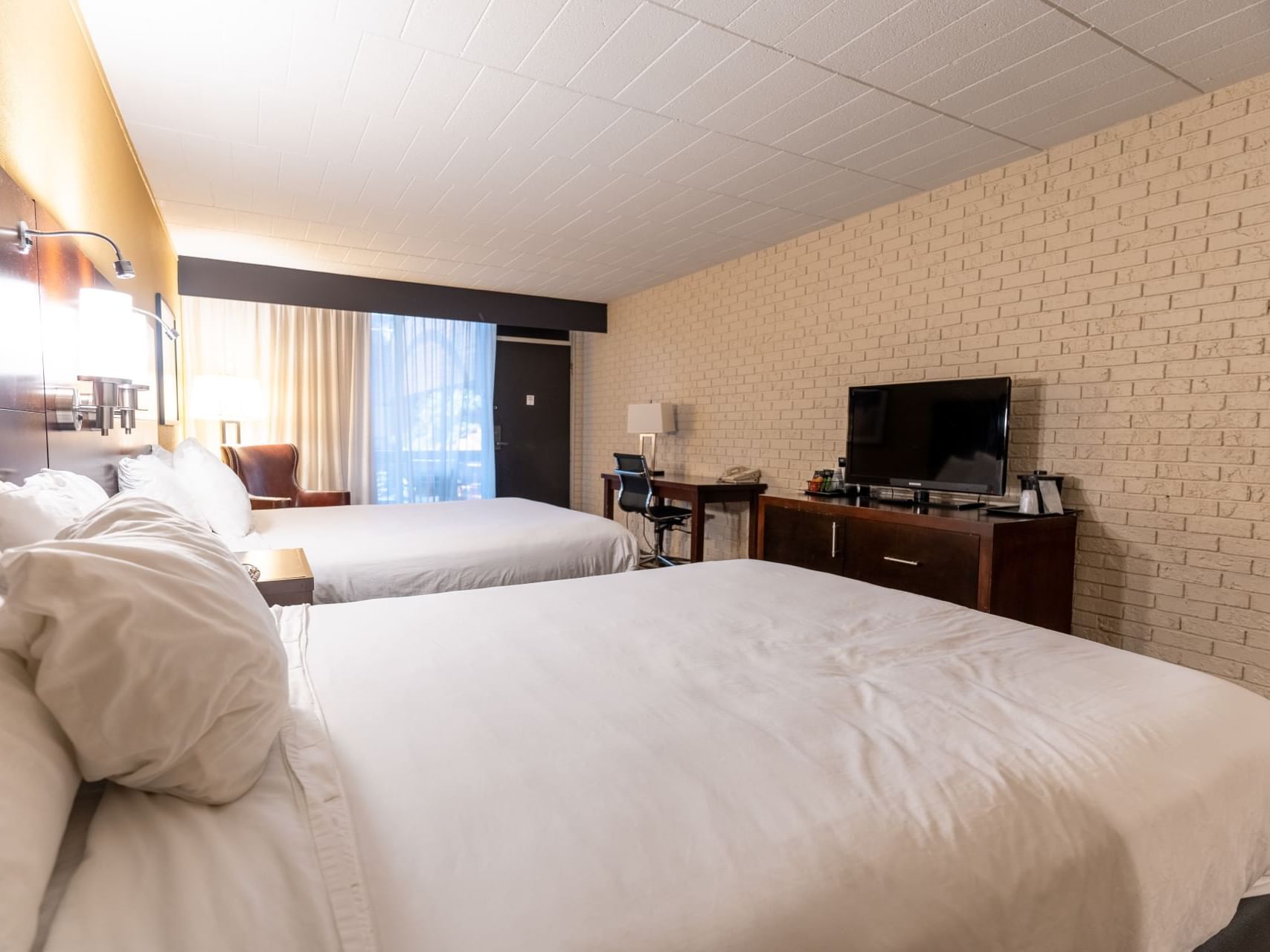 Two beds, desk, chair, and TV in Courtyard Queen Balcony room at M Hotel Buffalo.