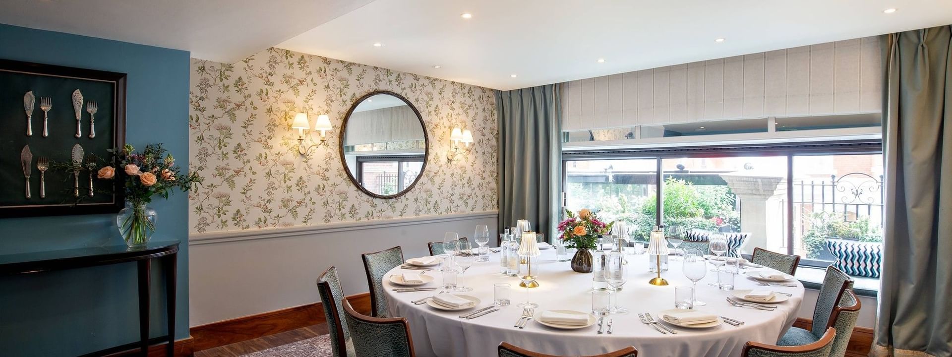 Round dining table by a floral wall under recessed lights in The Eaton Suites at Warwick Hotels & Resorts