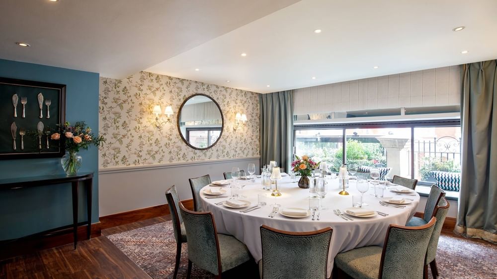 Round dining table by a floral wall under recessed lights in The Eaton Suites at Warwick Hotels & Resorts