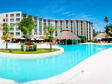 Exterior view of the hotel, cabanas & outdoor swimming pool at Gamma Hotels
