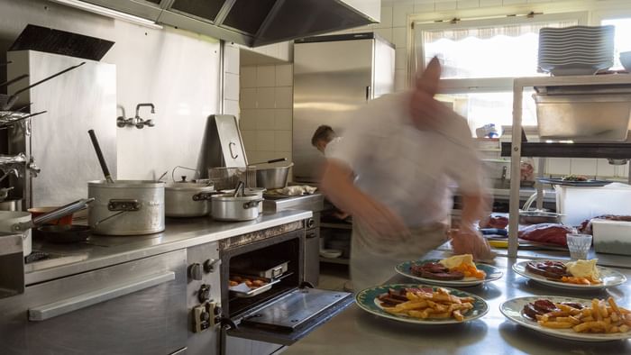 A chef prepares food in the kitchen at Hotel de france