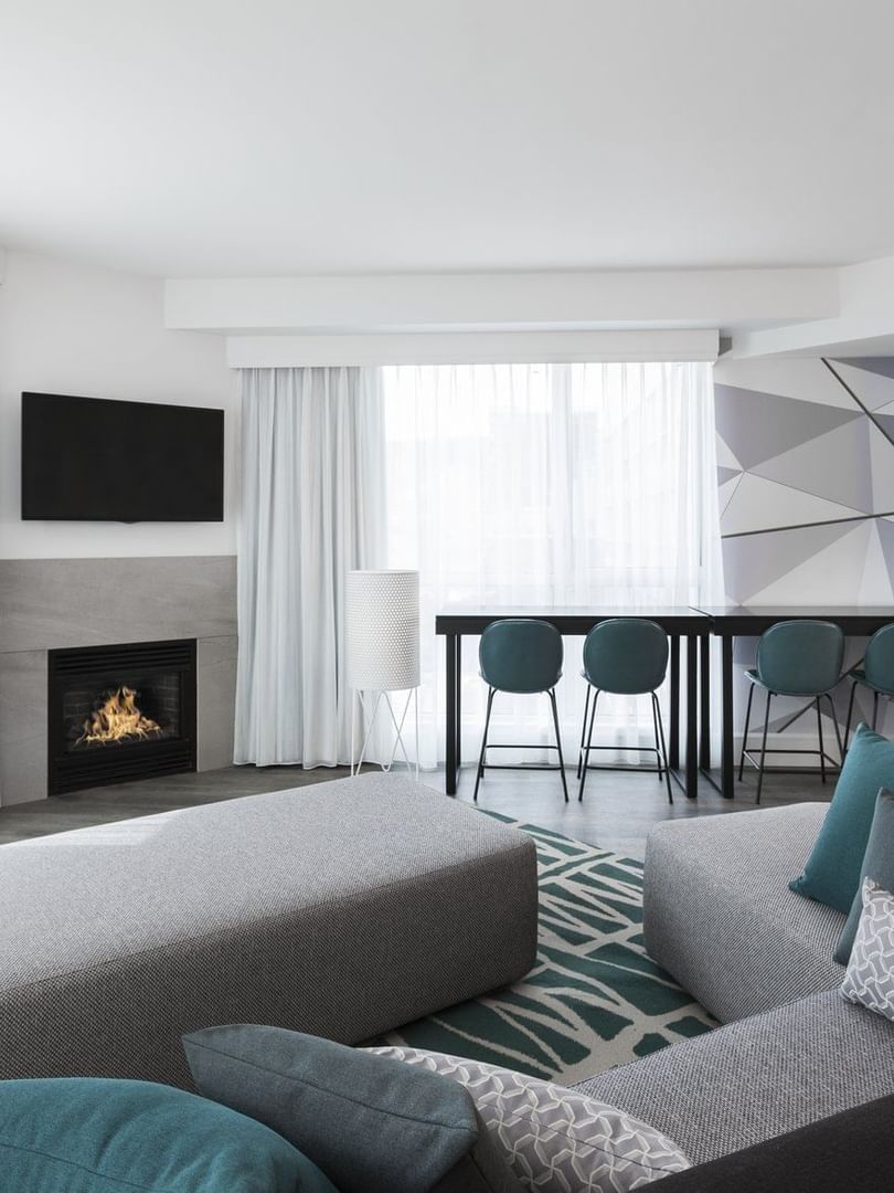 Warwick Premier Suite living area with a sofa facing the TV and fireplace at Warwick Le Crystal Montreal