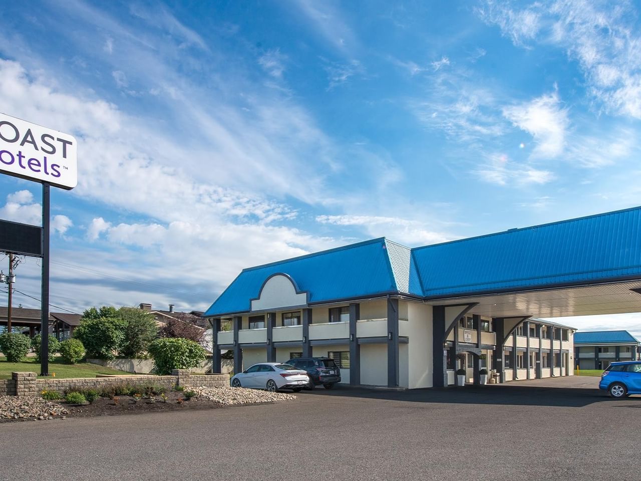 Exterior entrance of Coast Red Deer Hotel with roadside sign