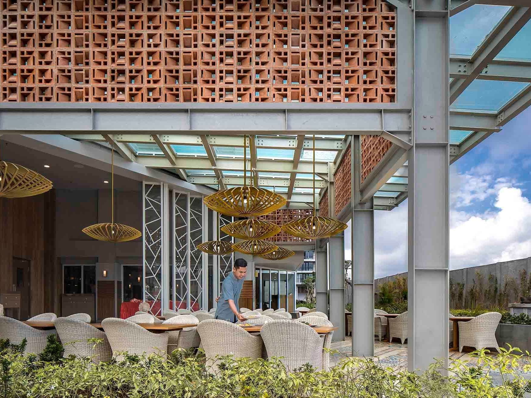 Staff member arranging dining area in Salt Restaurant & Pool Bar near Eastin Ashta Resort Canggu