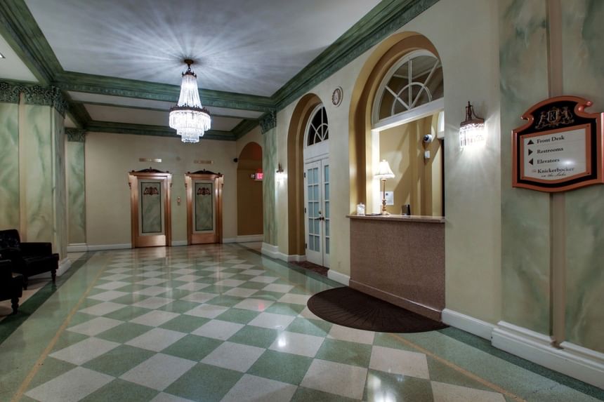 Grand hallway at Knickerbocker On The Lake with crystal chandeliers, arched mirrors, and polished stone floors