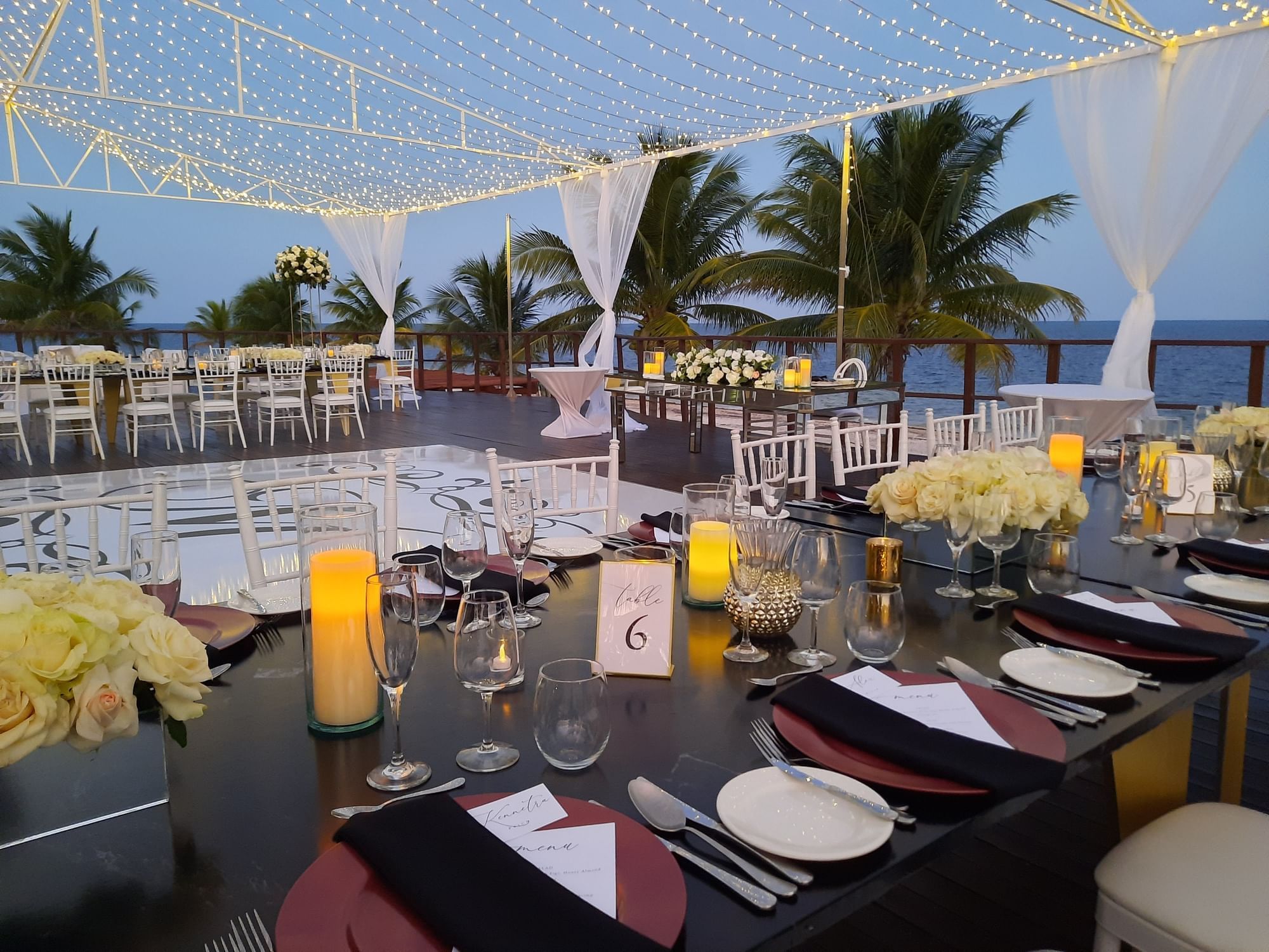 Banquet-style dining set-up with fresh flowers, candles & cutlery on vora deck at Haven Riviera Cancun
