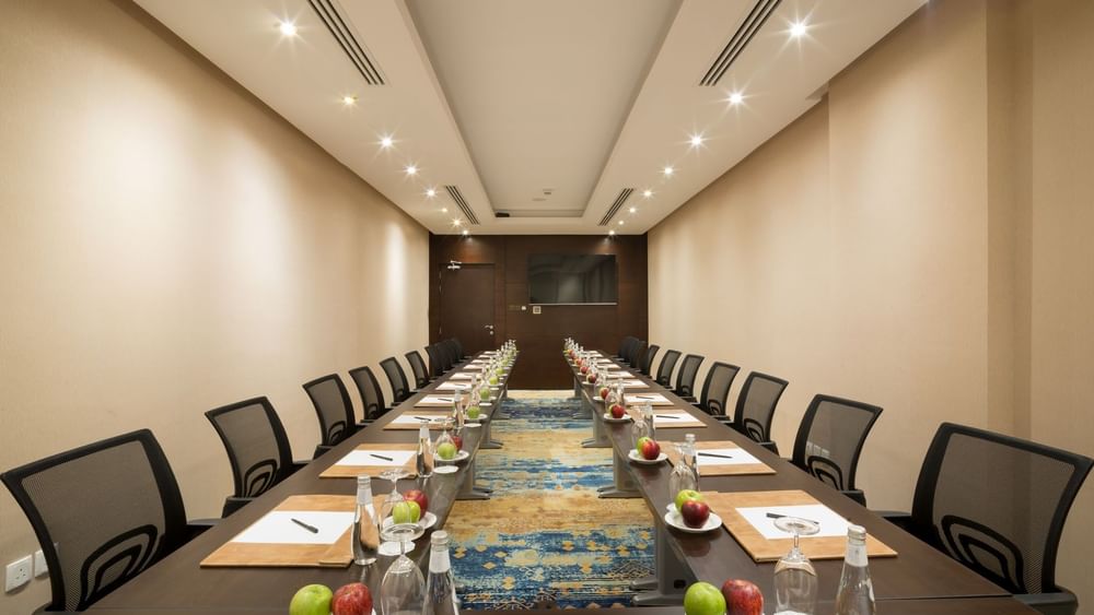 U-shaped table setup facing hanging TV in Khalej Meeting Room at Naviti by Warwick Dammam 