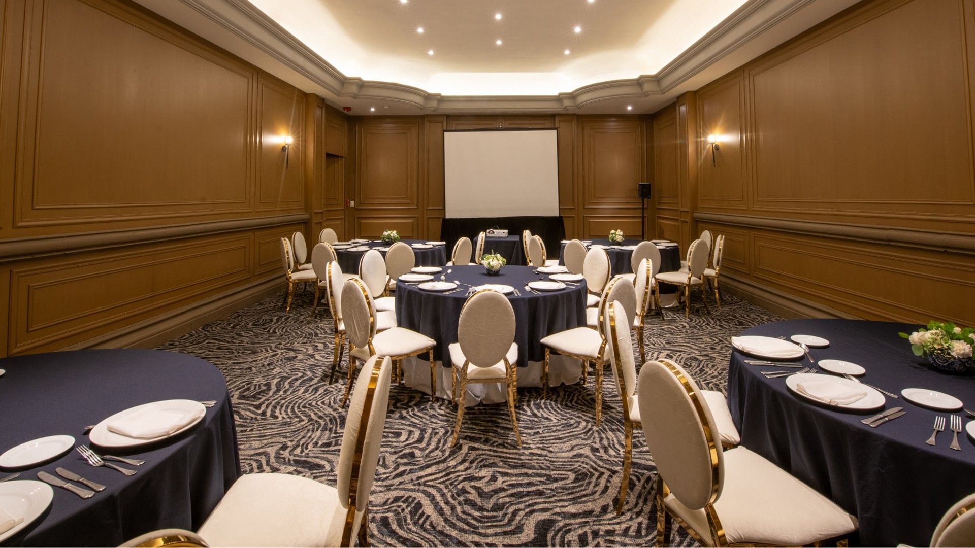 Salon Virreinal with round tables, white chairs, and a projector for presentation at Quinta Real Monterrey