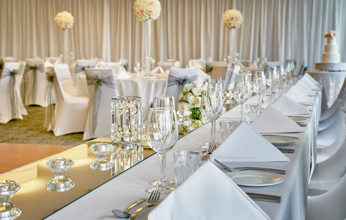 Elegant long wedding table, featuring crystal vases, candle holders, and a tiered cake at The Sebel Mandurah