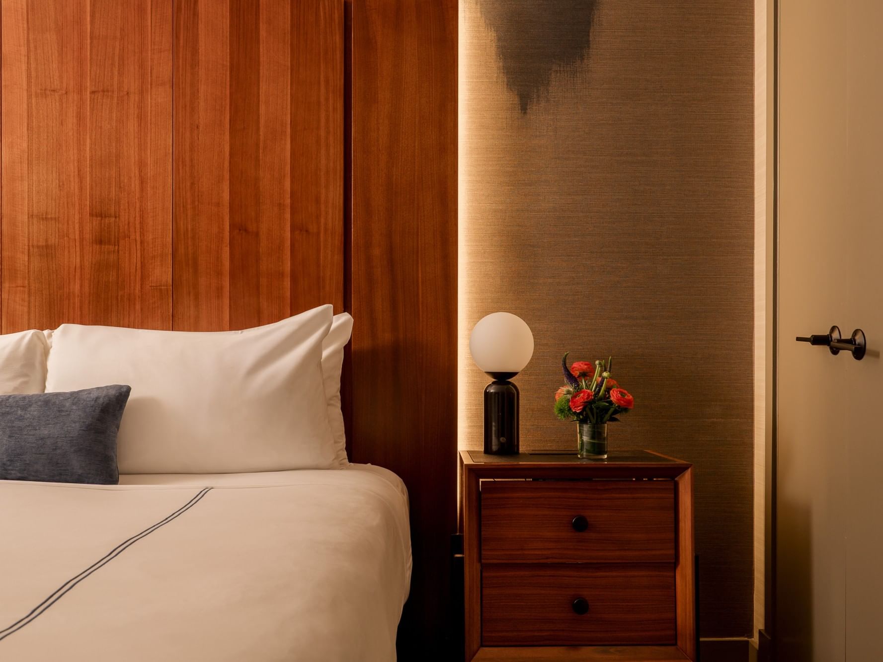 Two-Bedroom Manhattan Suite at Gansevoort Meatpacking NYC, New York, featuring a bed, nightstand, and flowers.