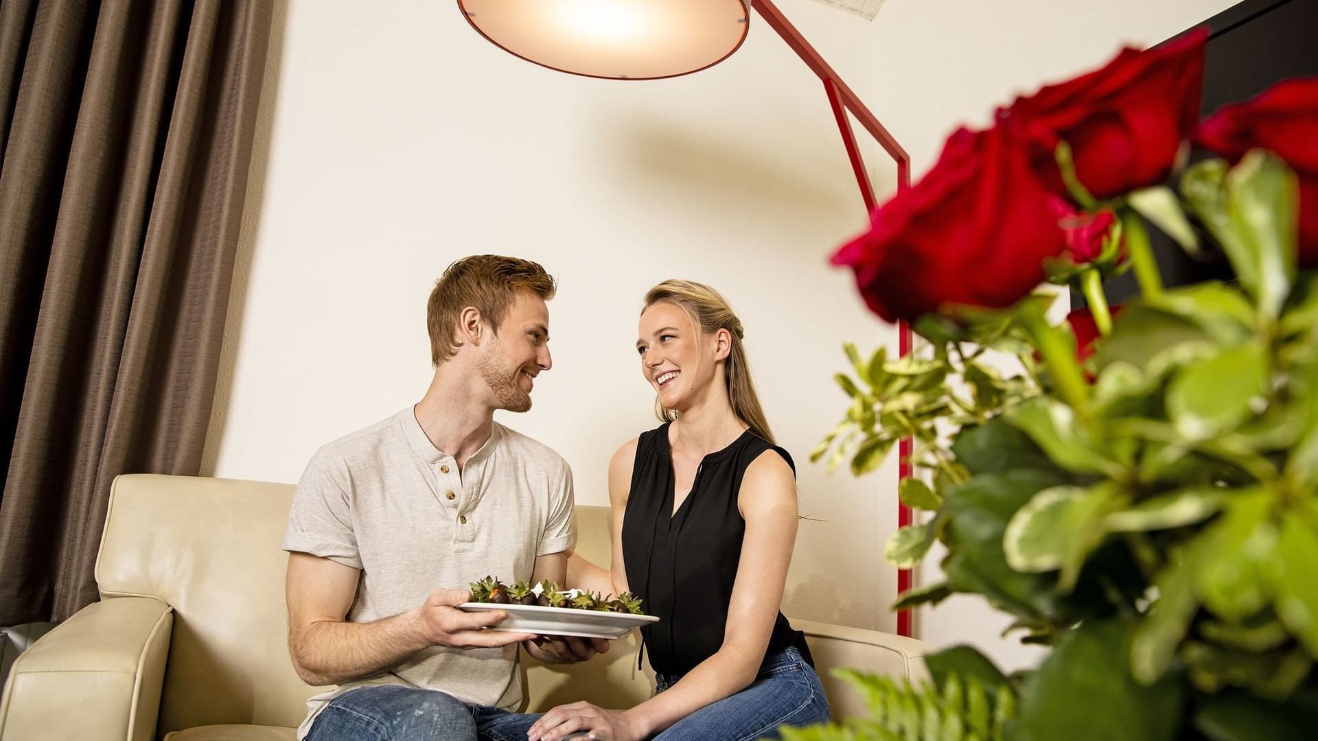 Couple feeding each other chocolate covered strawberries in Champagne Tower Suite at Cove Pocono Resorts