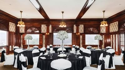 Banquet hall set up with black and white decor, round tables with floral centerpieces, and wooden walls at The Stanley Hotel