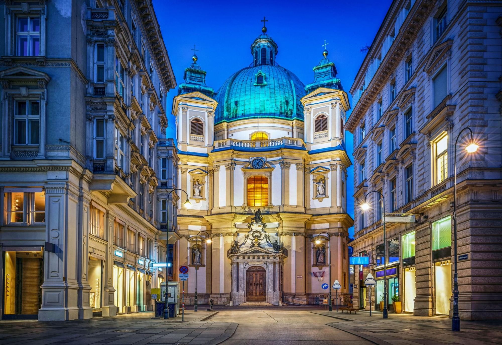 St. Peter’s Church in Vienna at night with its illuminated dome and baroque facade in a quiet street.