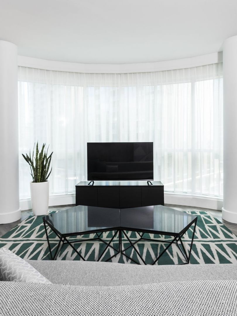 Élégant salon avec canapé, télévision et fauteuil dans la suite Crystal du Warwick Le Crystal