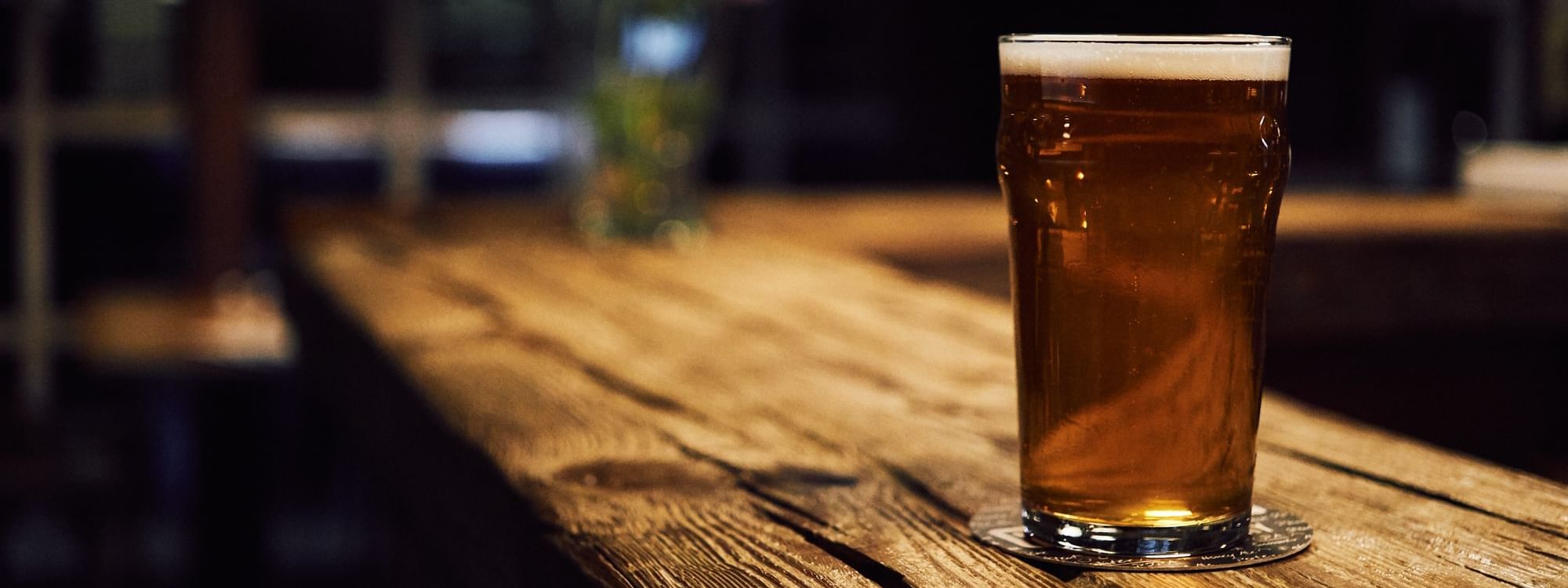Close-up of golden beer on a rustic wooden table served at Novotel Sunshine Coast Resort