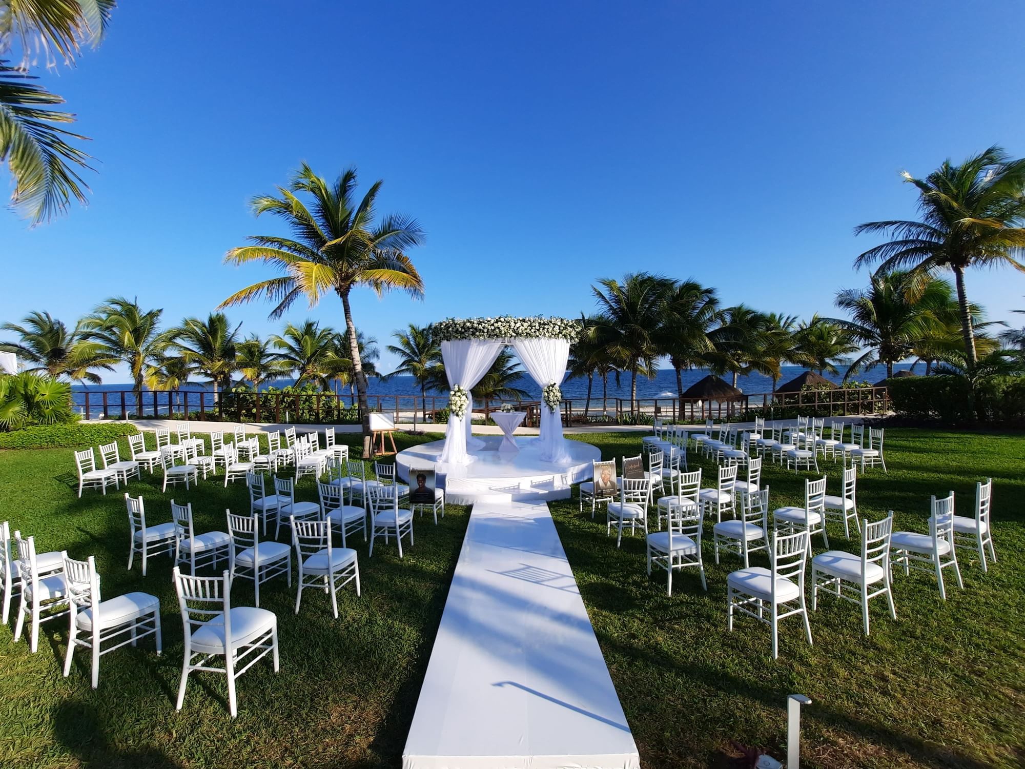 All white outdoor wedding set-up with aisle runner & chairs in main garden at Haven Riviera Cancun