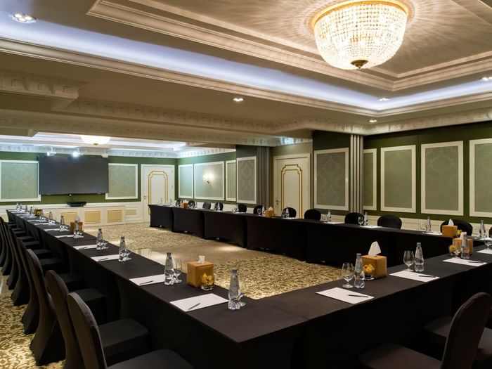 U-shaped conference table by black chairs under a crystal chandelier in Gems Ballroom at Warwick Hotels & Resort