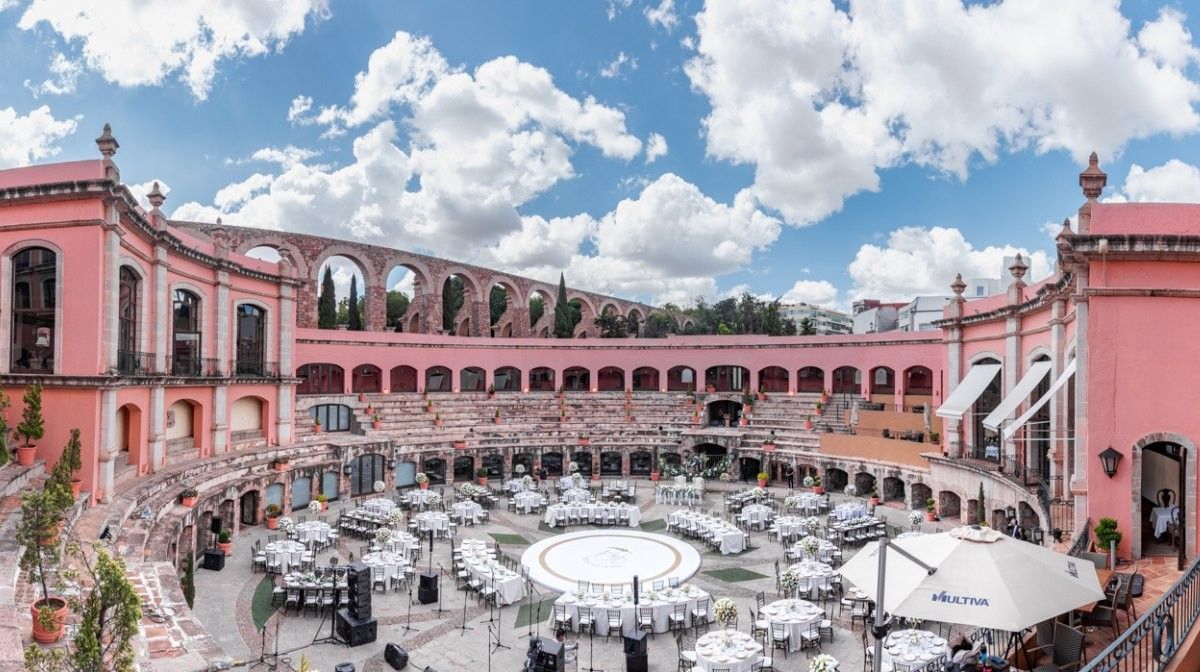 White tables by stone arches under a cloudy sky surrounding the plaza at Camino Real Pedregal Mexico