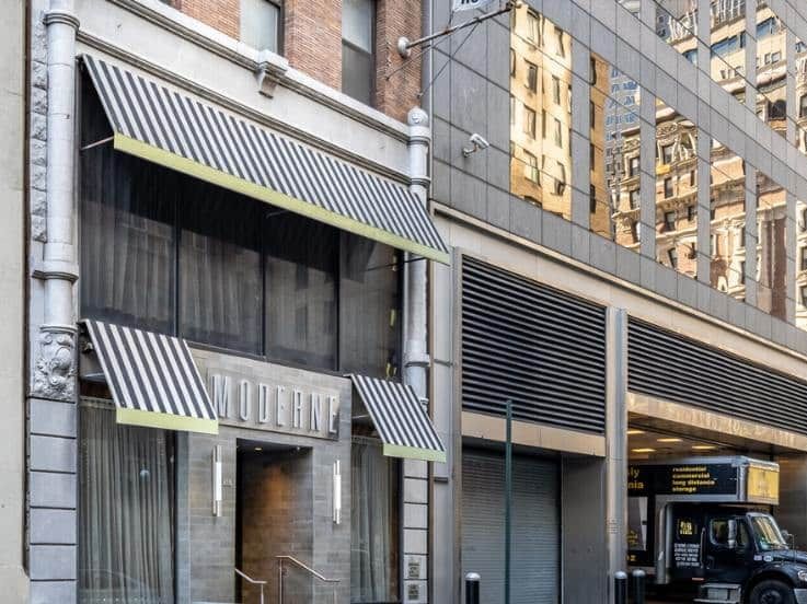A building with a sign that reads 'Moderne' and a truck parked outside