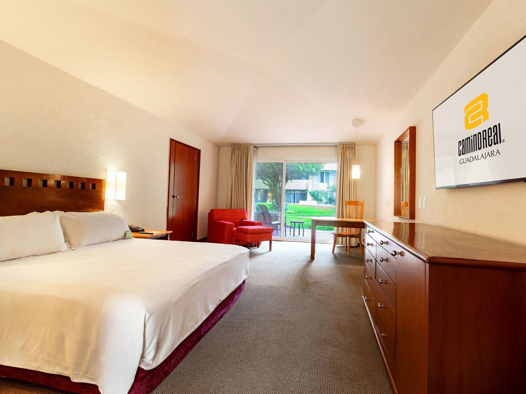 King Camino Real Club Executive featuring a red armchair, a wooden dresser, and garden access at Camino Real Guadalajara
