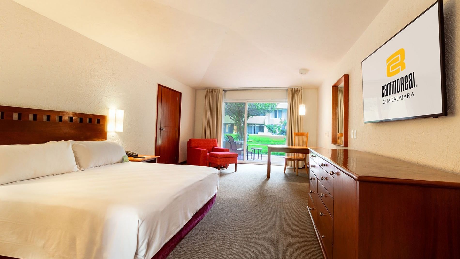 King Camino Real Club Executive featuring a red armchair, a wooden dresser, and garden access at Camino Real Guadalajara