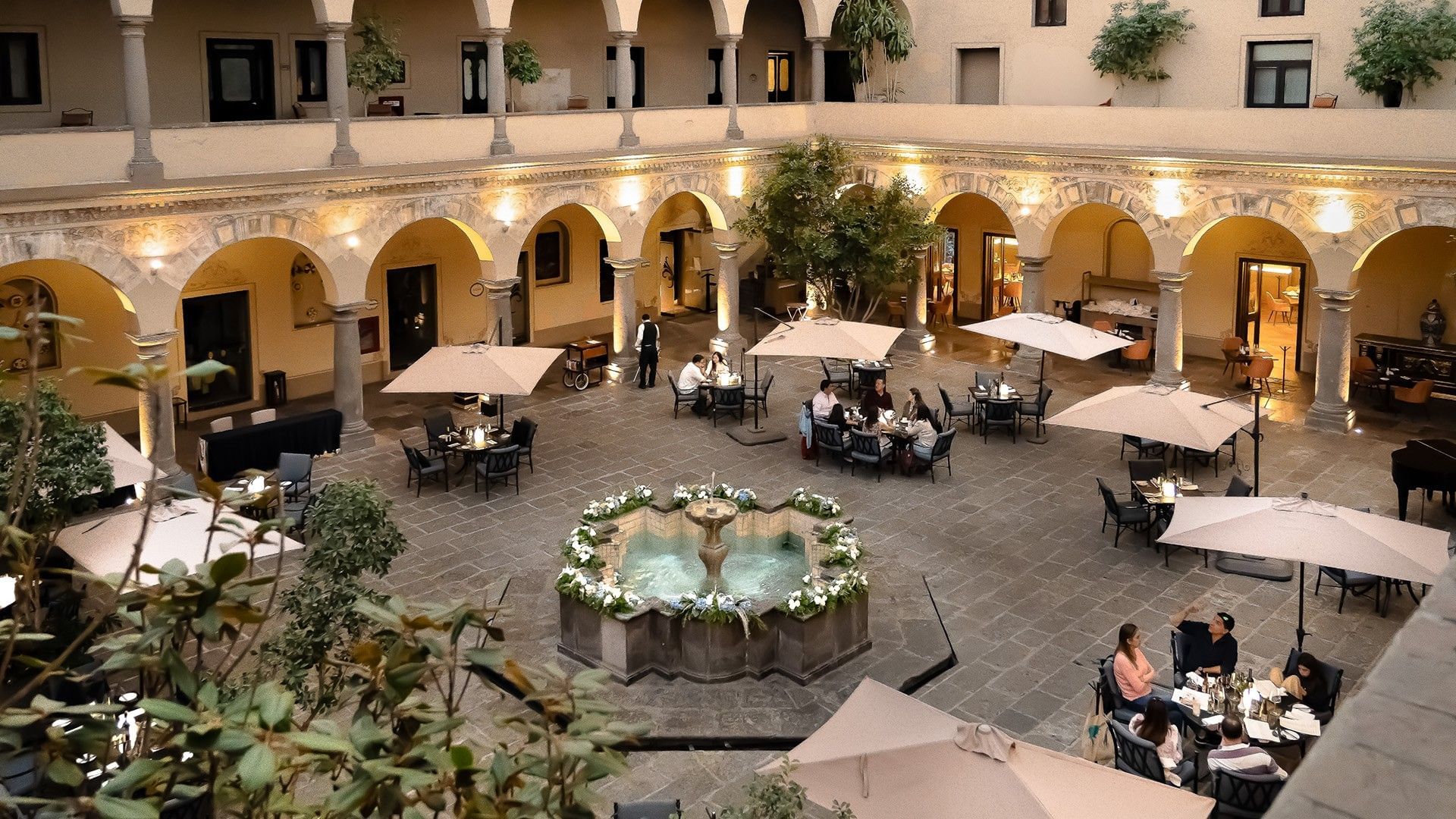Aerial view of a luxury hotel courtyard restaurant with a stone fountain and patio seating at Quinta Real Puebla