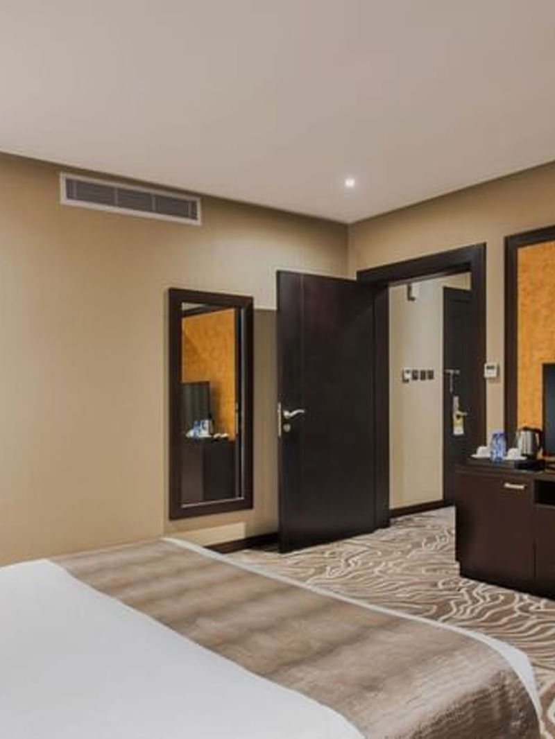 Junior Suite features a large bed by a TV stand under two air vents at Naviti by Warwick Al Khobar