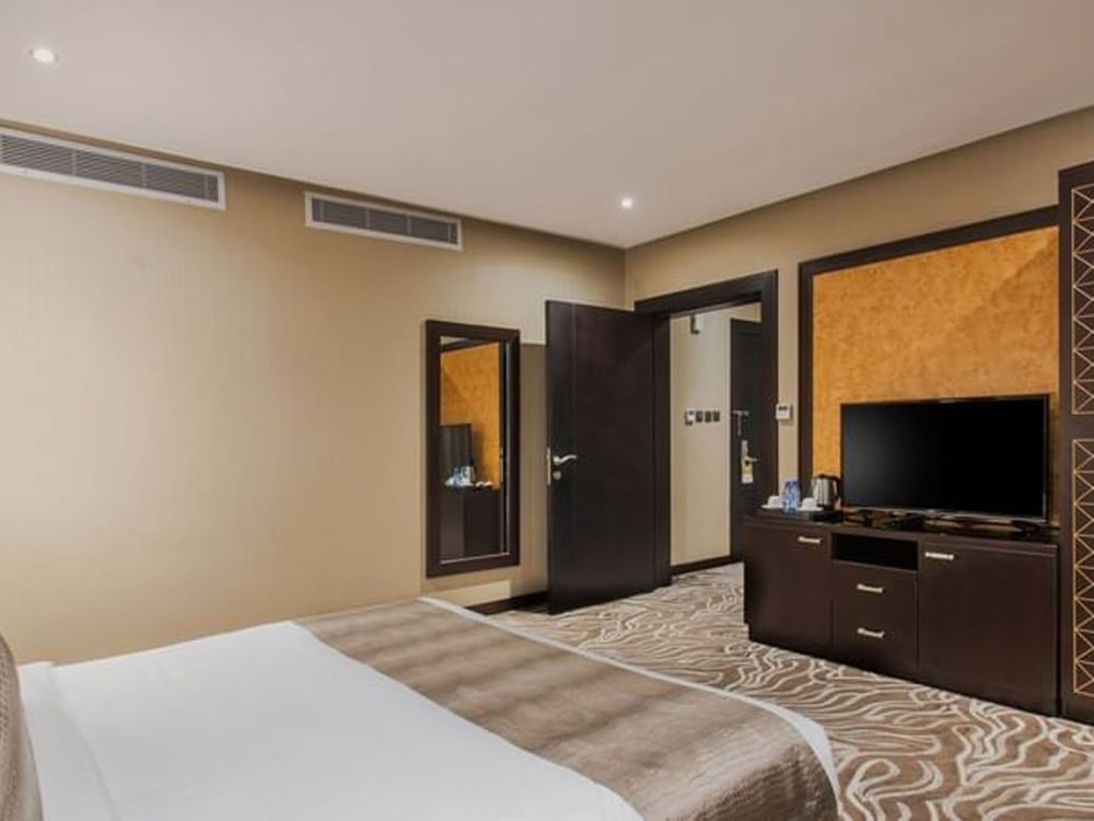 Junior Suite features a large bed by a TV stand under two air vents at Naviti by Warwick Al Khobar