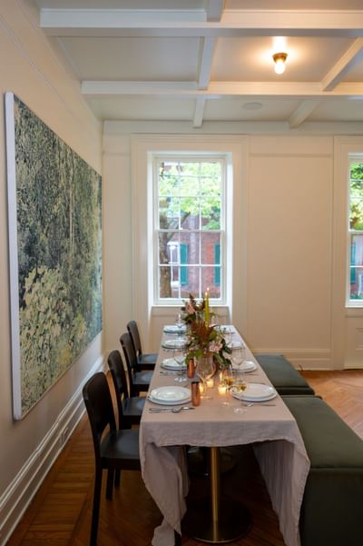 Private dining room with coffered ceiling, abstract art, and elegantly set table at The Ashbrook Hotel