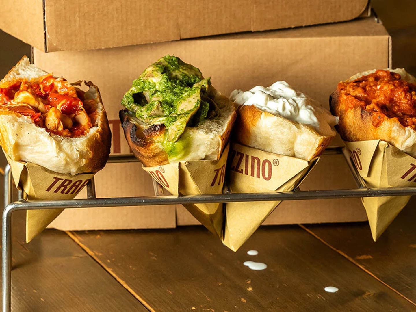 Four stuffed bread cones with various toppings, and spiced filling on a metal rack near The Guardian Hotel