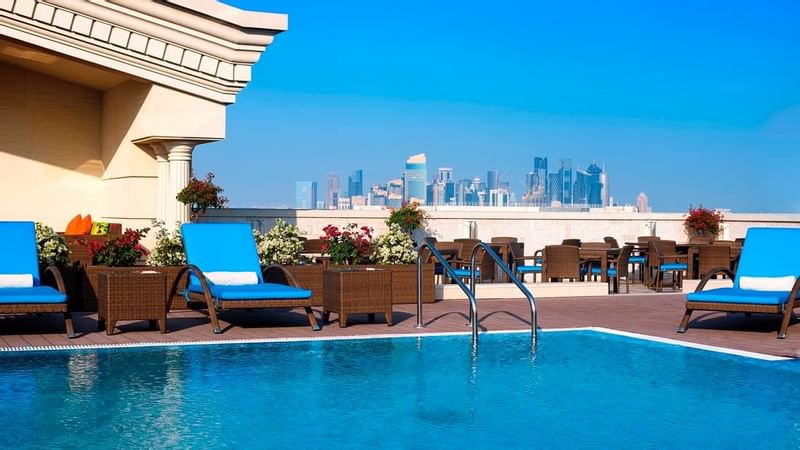 Outdoor pool with lounge chairs at Warwick Doha
