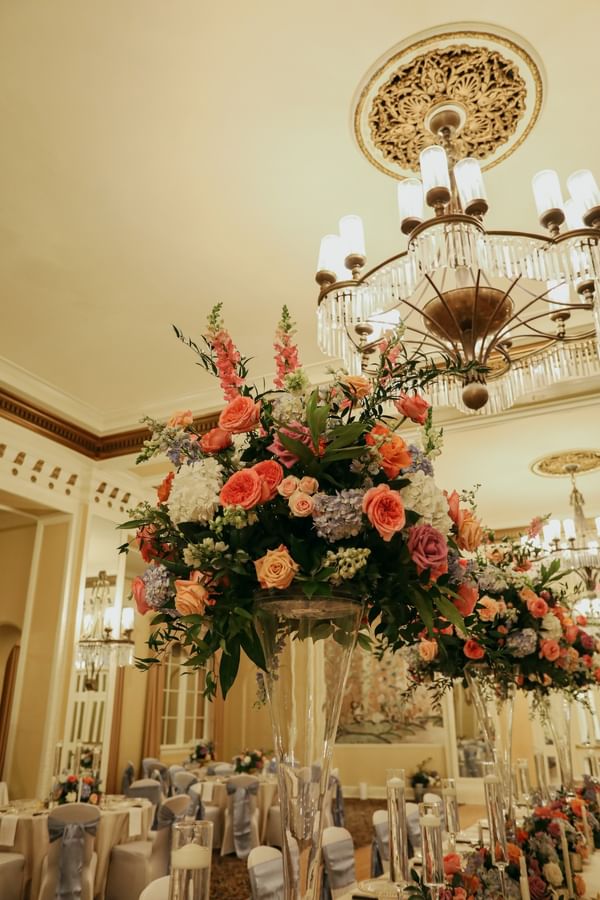 Tall floral centerpieces in glass vases by set tables under a crystal chandelier at Arlington Resort Hotel & Spa